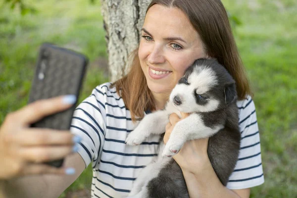 티셔츠를 강아지를 미녀는 공원에 사진이나 셀카를 핸드폰으로 찍거나 사진을 찍는다 — 스톡 사진