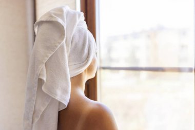 Havluya sarılmış genç bir kadının arka görüntüsü harikanın önünde duruyor. Genç bayan sabah duşundan sonra.
