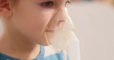 Küçük bir çocuk solunum tedavisi için nebulizör maskesi kullanır. Video, çocuğun ilaçlarını solumasını, ev sağlık hizmetlerini ve pediatrik solunum hizmetlerini ön plana çıkarıyor..