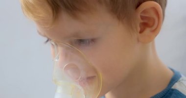 Küçük bir çocuk solunum tedavisi için nebulizör maskesi kullanıyor, evde ilaç soluyor. Videoda, aile ortamında pediatrik sağlık ve solunum terapisi vurgulanıyor.