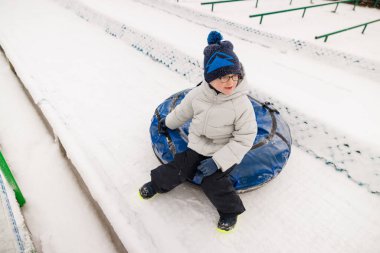 Kışlık giysiler içindeki küçük bir çocuk kar tünelinde oturur ve karlı bir yamaçta eğlenceli bir yolculuğa hazırdır. Sahne, kış etkinliklerinin neşesini ve heyecanını yakalıyor..