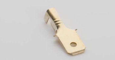 Açık arkaplanda altın renkli bir metal elektrik konnektör terminali gösterilir. Video klipte, endüstriyel ya da teknik kullanım için ayrıntılarını vurgulayan birden fazla açıdan bağlantı kurulmuş olabilir..