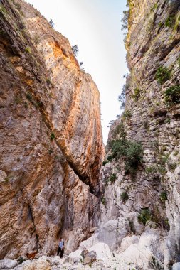 Vall de Laguar 'da. Alicante, İspanya, 20-02-2021. Isbert Barajı 'nın kıvrımlı beton duvarına bakan dramatik, alçak açılı bir manzara, yüksek kanatlı, katıksız kaya kayalıkları, gökyüzünün ince bir parçasına kadar dar, görünür graffiti ile çevrili. 