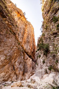 Isbert Vadisi girişinin engin ölçeğini gösteren dramatik alçak açılı bir manzara, yüksek katmanlı kanyon duvarları, solda sıcak ve dramatik bir ışıkla yıkanmış..