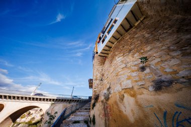 : İçinde taş bir merdiven, antik şehir duvarı ve açık bir gökyüzünün altındaki ana köprünün kemeri olan bir kompozisyon..
