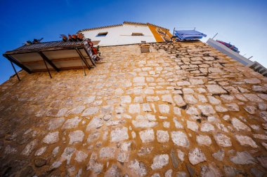 Villajoyosas 'ın çarpıcı bir yükseliş perspektifi. Büyük bir taş duvarın üzerine inşa edilmiş ünlü asma evleri..