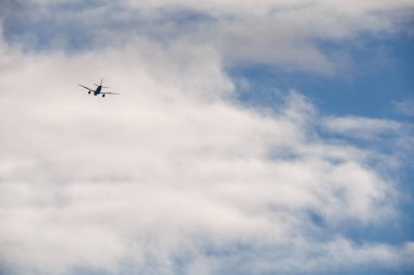 Villajoyosa, Alicante, İspanya 2025-12-26.Büyük beyaz kümülüs bulutları tarafından çerçevelenmiş, gökyüzünde uçan ticari bir jete geniş bir perspektif.