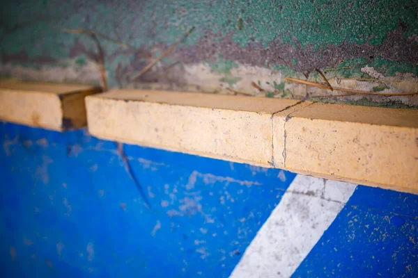 Sığ bir alan derinliği mavi boyanmış zeminli ve beyaz köşegen çizgili sarı beton bir ayırıcıya odaklanmış desen ve rengi vurguluyor..