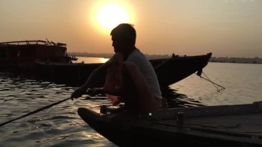 Varanasi Ghat 'taki nehirde aileleri için balık arayan bir kayıkçı..