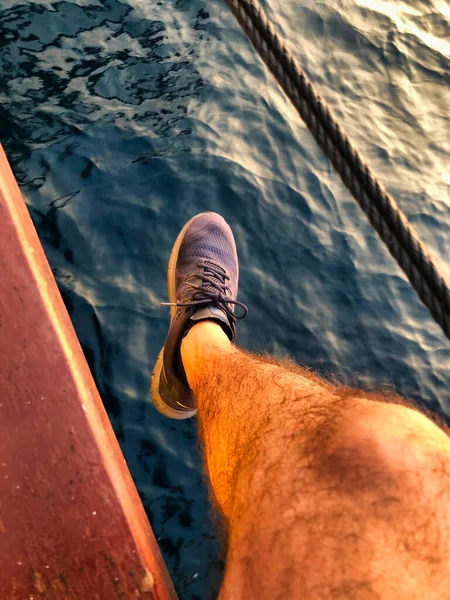 Teknede sallanan bir adamın ayakları ve bacakları 