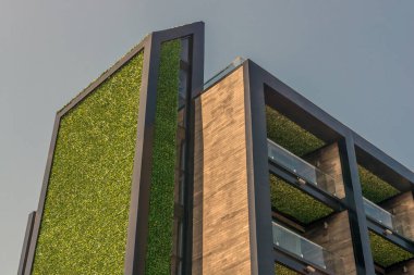 Modern yüksek binalar. Güzel mimari. Yüksek teknoloji ürünü yeşil elementler. Ön cephede balkonlar ve binanın çatısında teraslar..