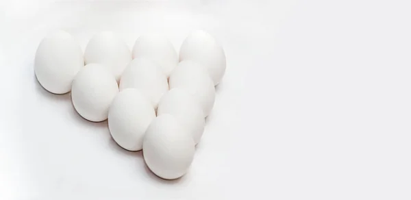 三角形の形で白い背景に10個の白い卵 健康食品 健康的なライフスタイル 殻の中のタンパク質と黄身 テキストの場所 — ストック写真