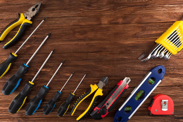 Work tool of the wizard. Screwdrivers, pliers, wire cutters, building level, tape measure, hammer, wrenches, square and other tools on a wooden surface. Free space for text.