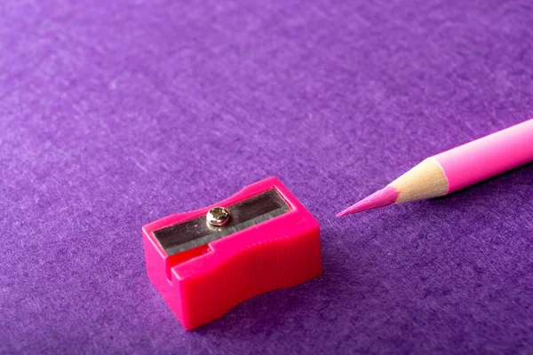 红色铅笔 紫色背景上有削笔器 办公室工具 — 图库照片