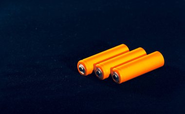 Three Orange AA batteries. Electricity charging. Battery for toys, electronics and equipment. Backup power supply.