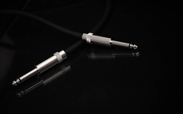 Two silver TRS connectors for the analog audio signal are placed against a black background. Professional jack connectors for sound equipment. Audiophile technologies concept.
