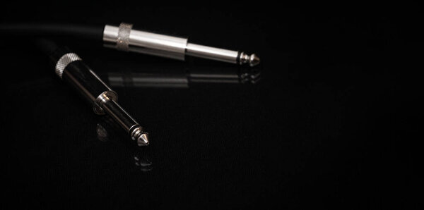 Two silver TRS connectors for the analog audio signal are placed against a black background. Professional jack connectors for sound equipment. Audiophile technologies concept.