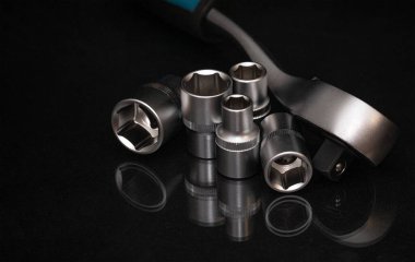 Karanlık bir yüzeyde duran soket başlı metal cırcır anahtarı. Tamir, mekanik, bakım, mühendislik ve profesyonel atölye çalışması için araç konsepti.