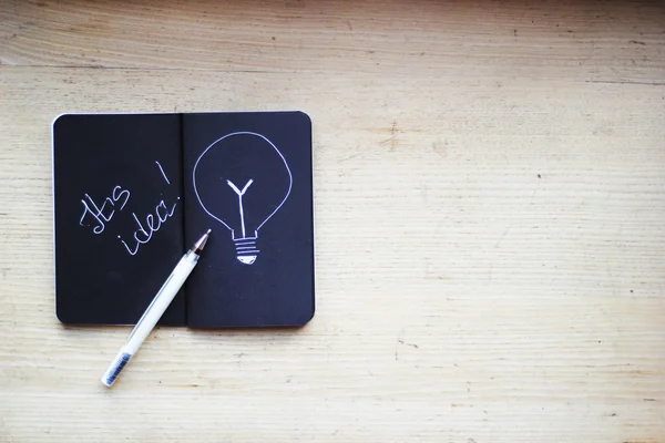 Bolígrafo y cuaderno en la mesa con inscripción "Es idea !" — Foto de Stock
