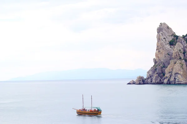 The boat with tourists trevel at the open sea with mountains in the background