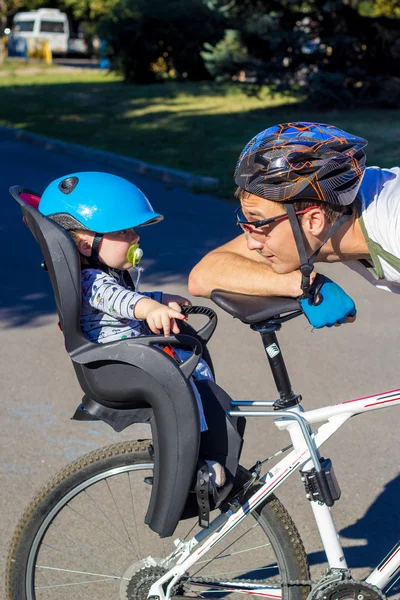 Pai e filho andando na bicicleta com cadeira de bicicleta Fotos De Bancos De Imagens