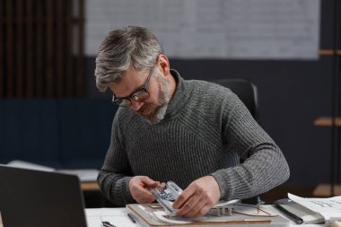 3D mimar, 3D model bir binada çalışıyor. Mühendis bina planını inceliyor, inşaat projesi için yeni fikirler arıyor. İş yerindeki yakışıklı sakallı adam. İş inşa kavramı