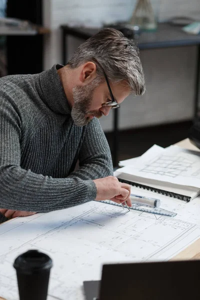 Mimar ofiste planlar çiziyor. Mühendis bir inşaat projesi çiziyor. Mimari plan. Yakışıklı sakallı adamın işine odaklanmış yakın plan portresi. İş inşa kavramı