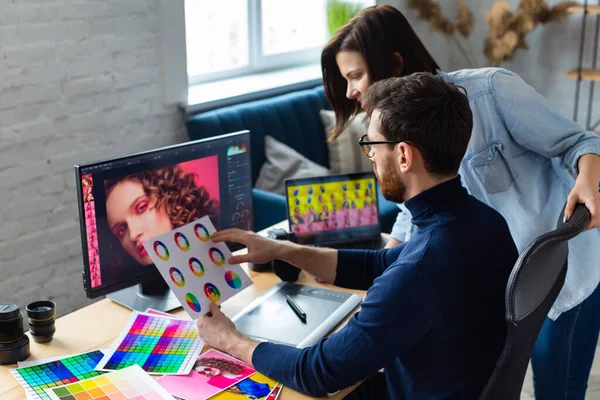 Fotograf och grafisk formgivare arbetar på kontoret med laptop, monitor, grafisk ritplatta och färgpalett. Skapa team diskuterar idéer i reklambyrå. Retuscherar bilder. Lagarbete — Stockfoto