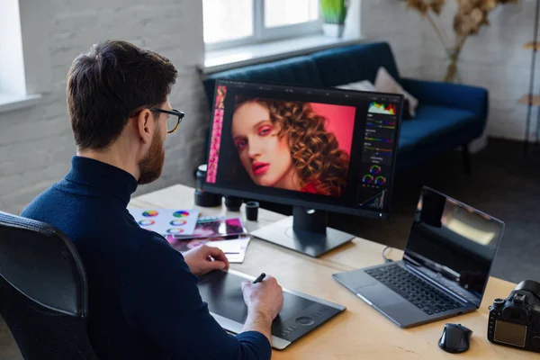 Retouching images in special program.Portrait of graphic designer working in office with laptop, monitor, graphic drawing tablet and color palette.Retoucher workplace in photo studio.Creative agency — стоковое фото