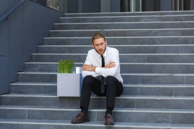 Beyaz gömlekli mutsuz genç bir yönetici işinden kovuldu. Üzgün bir işçi işten çıkarmalardan sonra bir iş merkezinin merdivenlerinde oturur. Kriz ve işsizlik