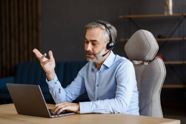 Çevrimiçi eğitim, uzaktan çalışma, evde eğitim. İnternette öğretmenlik yapan gri saçlı yakışıklı bir adamın portresi. Online toplantı, video görüşmesi, video konferansı, kurslar çevrimiçi