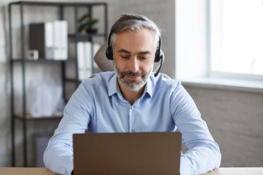 Çevrimiçi eğitim, uzaktan çalışma, evde eğitim. İnternette öğretmenlik yapan gri saçlı yakışıklı bir adamın portresi. Online toplantı, video görüşmesi, video konferansı, kurslar çevrimiçi