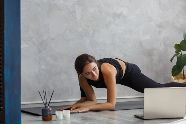 Giovane istruttrice di yoga femminile sportiva coaching online, facendo video di lezioni di yoga sulla fotocamera del computer portatile. Bella donna che pratica pose yoga. Posture yoga, meditazione, relax, benessere e salute — Foto Stock