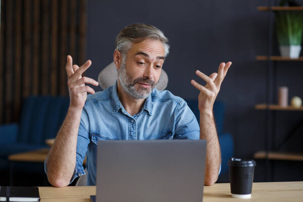 Portrait of grey-haired senior handsome smiling man working from home. Communication online with colleagues and video conference. Online meeting, video call, remote working