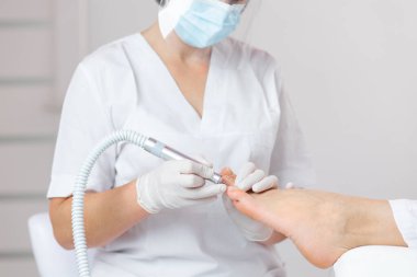 Özel elektrikli aletle ayak soyma. Elektrikli makine kullanan profesyonel donanım pedikürü. Tıbbi pedikür yapan hasta, podiyatriste gidiyor. SPA Salonu 'nda ayak tedavisi..