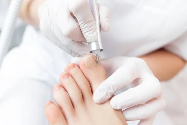 Peeling stóp ze specjalnym urządzeniem elektrycznym.Profesjonalny pedicure sprzętowy przy użyciu maszyn elektrycznych.Pacjent na zabiegu pedicure medycznego, wizyta podiatra Leczenie stóp w salonie SPA.. — Zdjęcie stockowe