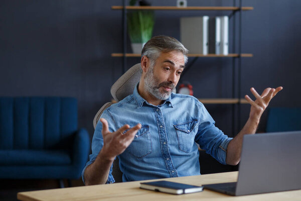 Portrait of grey-haired senior handsome smiling man working from home. Communication online with colleagues and video conference. Online meeting, video call, remote working