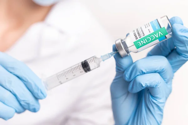 SARS - CoV2 Vaccination concept. Close up COVID-19 vaccine dose. A doctor or nurse in a laboratory holds a vial with a vaccine. Pandemic immunity.
