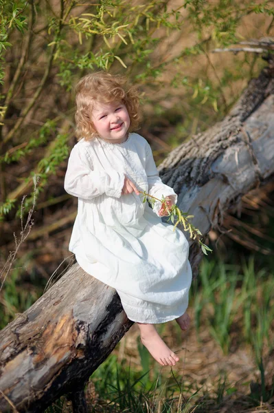 Jeune fille souriante portant une robe blanche élégante assise sur le tre — Photo