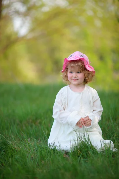 꼬마 소녀는 감에 앉아 세련 된 화이트 드레스를 입고 웃 고 — 스톡 사진