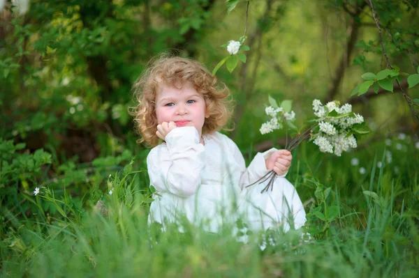 Petite fille portant une robe blanche élégante assise dans l'herbe esprit — Photo