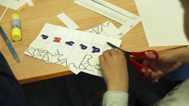 Kind Snijden Papier Brieven Met Een Schaar Aan Tafel — Stockvideo