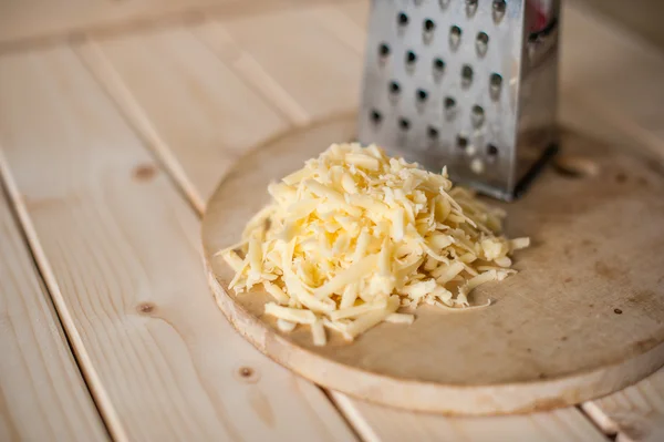 Queijo ralado em uma tábua de madeira — Fotografia de Stock