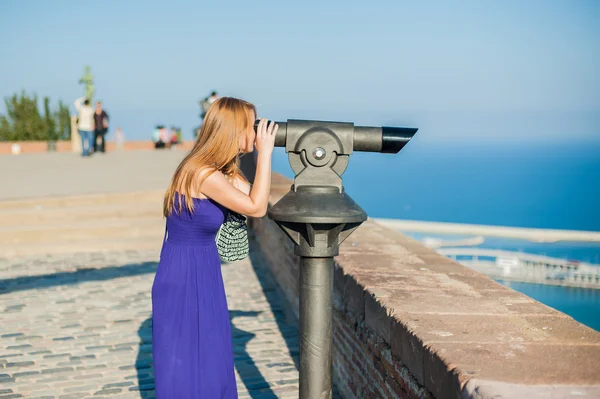 Das Mädchen blickt in ein stationäres Teleskop — Stockfoto