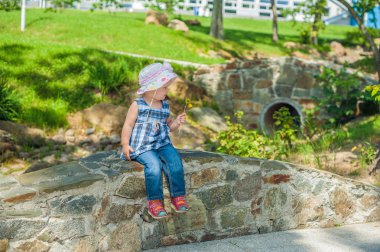 Bir taş köprü üzerinde oturan yürümeye başlayan çocuk kız
