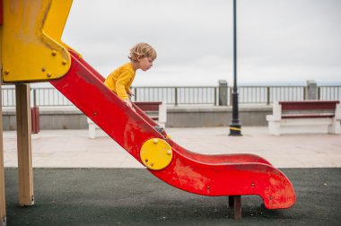 Toddler boy on children's slide playground clipart
