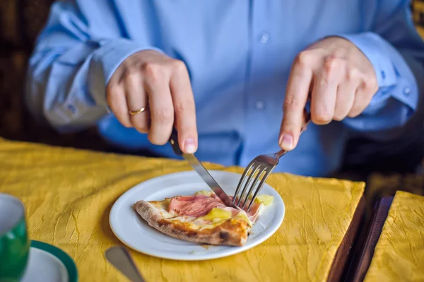 Man snijdt de pizza met kaas en ham — Stockfoto