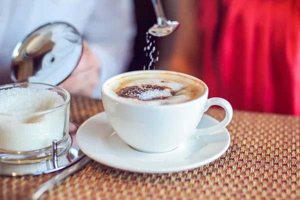 Wylewa cukru z łyżką w kawa, mężczyzna i kobieta holding kubki, z serca w kawiarni — Zdjęcie stockowe