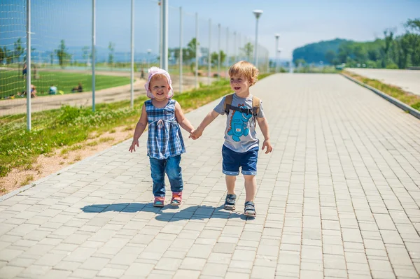 Kleine Jungen und Mädchen gehen auf einem Weg am Fußballplatz vorbei — Stockfoto