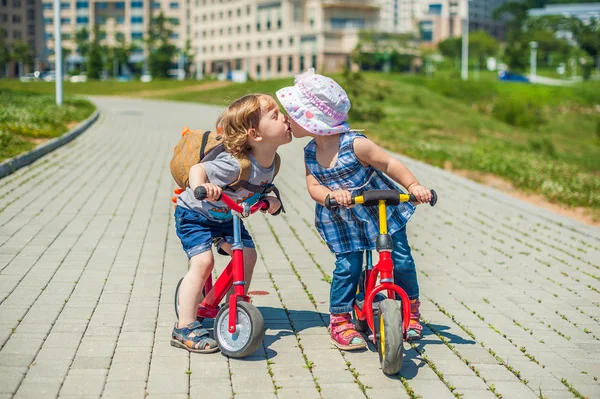 Хлопчик і дівчинка цілуються на рівноважних велосипедах в літньому парку — стокове фото